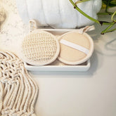 Facial cleansing pads, beige and white round pads, with loop and strap detail, in a dish