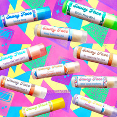 Lip balm tubes with white, blue, and orange labels from Saucy Face Co.