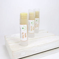 Lip balm tubes with beige balm, clear plastic casing, and Flaherty Naturals labels on a white wooden surface