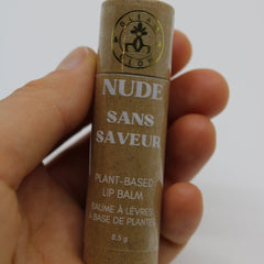 Lip balm tube, brown cardboard, white text, held in hand, GLEAM & GLOW brand visible