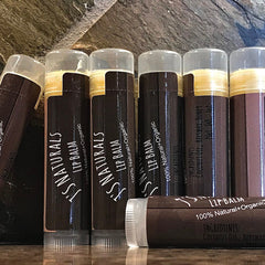 Lip balm tubes with brown textured paper, gold band, and clear caps, J's Naturals branding visible