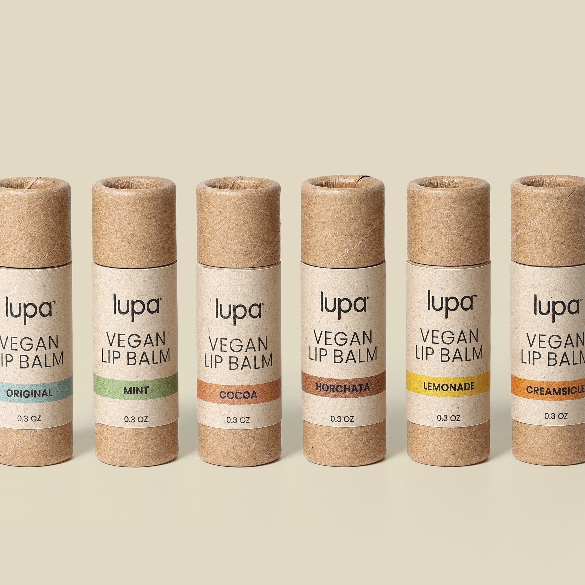 Vegan lip balm tubes in brown cardboard with colorful flavor labels, Lupa brand