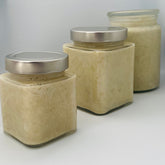 Body butter jars with silver lids, light beige color, and square glass shape