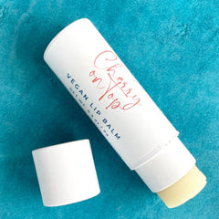 Lip balm in white tube with red script, exposed balm, and blue background.
