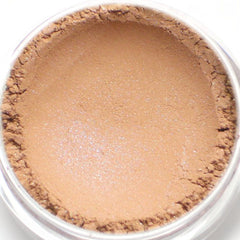 Side angle of peach tan eyeshadow pan with blue shimmer particles, showcasing vegan mineral makeup texture