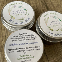 Multipurpose salve tins with white labels, silver metal, and Simple Nature Herbals text on top