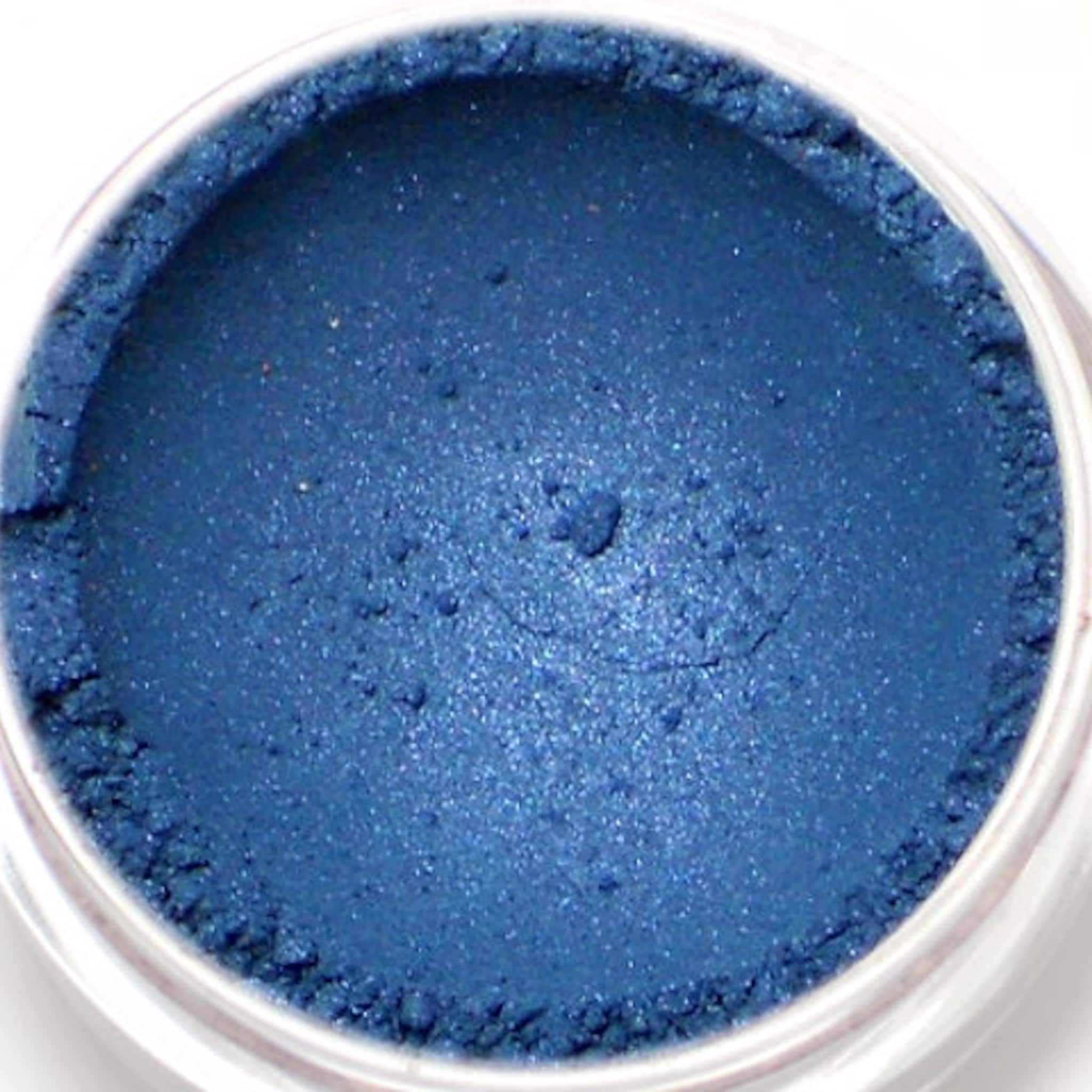 Eyeshadow blue shimmer powder in a clear jar, close-up view