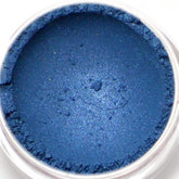 Eyeshadow blue shimmer powder in a clear jar, close-up view