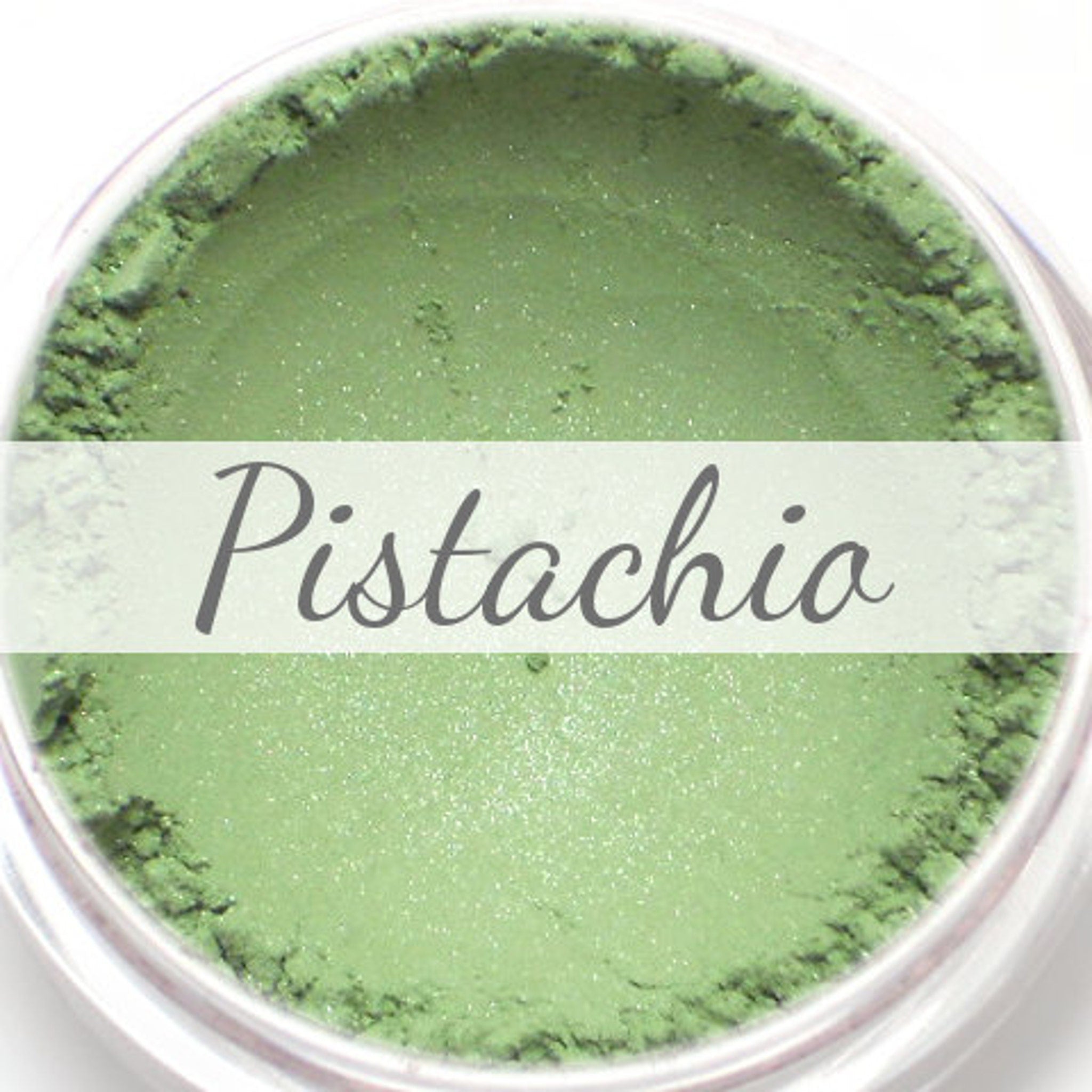 Close-up of shimmery pistachio green vegan eyeshadow in compact with reflective finish
