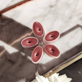 Lip balms, berry-tinted oval tubes, arranged in a star shape on marble surface