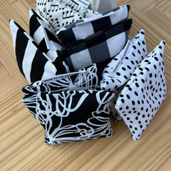 Decorative fabric pouches in black and white patterns, including stripes, polka dots, and music notes, "Designed by Claire" label