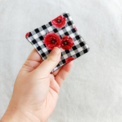 Coaster with red floral print, black and white gingham pattern, held in hand
