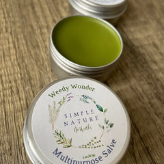 Multipurpose salve in silver tin with green balm, Simple Nature Herbals label on wood surface