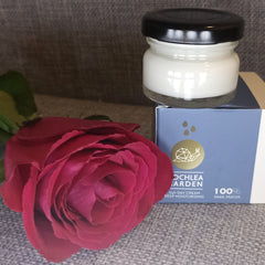 Hand applying pearl-sized dollop of creamy white moisturizer onto glowing cheek