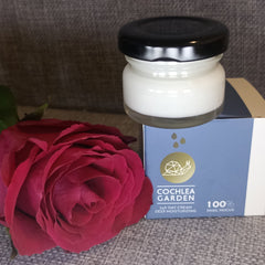 Close-up of creamy white moisturizer with natural extracts in a sleek blue jar, texture visibly rich and smooth