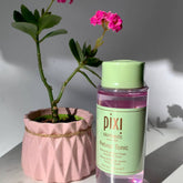 Retinol Tonic bottle with green cap and label, pink liquid, and plant in pink pot with rope trim