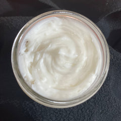 Close-up of whipped body butter in a white jar, showcasing its creamy texture and natural ingredients