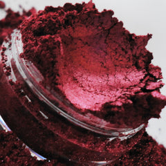 Red powder in a clear jar, showing texture and shimmer, spilling out