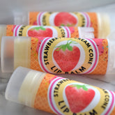 Lip balm tubes with strawberry labels, orange waffle cone pattern, and clear caps