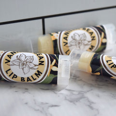 Lip balm tubes with floral pattern and "Vanilla Bean" text on marble surface