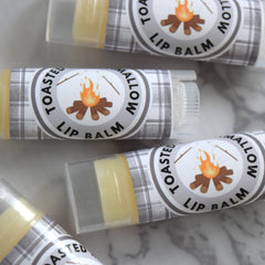 Lip balm tubes with plaid pattern labels, orange and brown campfire graphic, and "Toasted Marshmallow" text