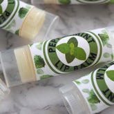 Peppermint lip balm tubes with green and white labels, clear plastic casing, Wandering Pines Cottage text