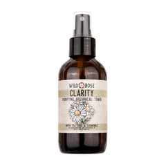 Botanical toner spray bottle with brown glass, white label, and black pump top featuring Wild Rose Clarity text