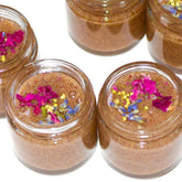 Honey scrub in glass jars, brown and pink floral accents, skincare product