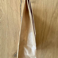 Brown paper bag with folded top, against a wood grain background