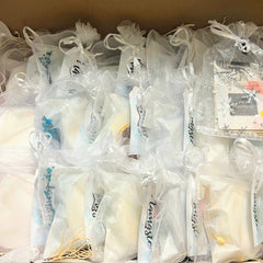 Loofah soap favors in white organza bags with dried flowers and ribbon ties, gift favors