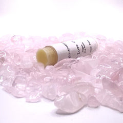 Lip balm tube with white label, yellow balm, and pink crystals around it