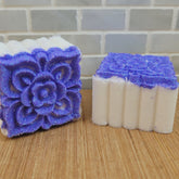 Shower bombs with white and purple floral design on wooden surface