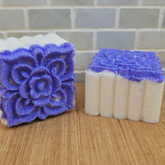 Shower bombs with white and purple floral design on wooden surface