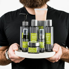 Beard care products with black and white striped bottles, green labels, and a man holding them