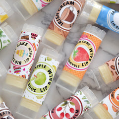 Lip balm tubes with various flavors, white labels, and colorful fruit and dessert designs.