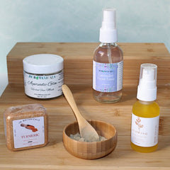 Face care products on wooden surface, including JM Botanicals Ayurvedic Glow jar, oil, and toner bottles