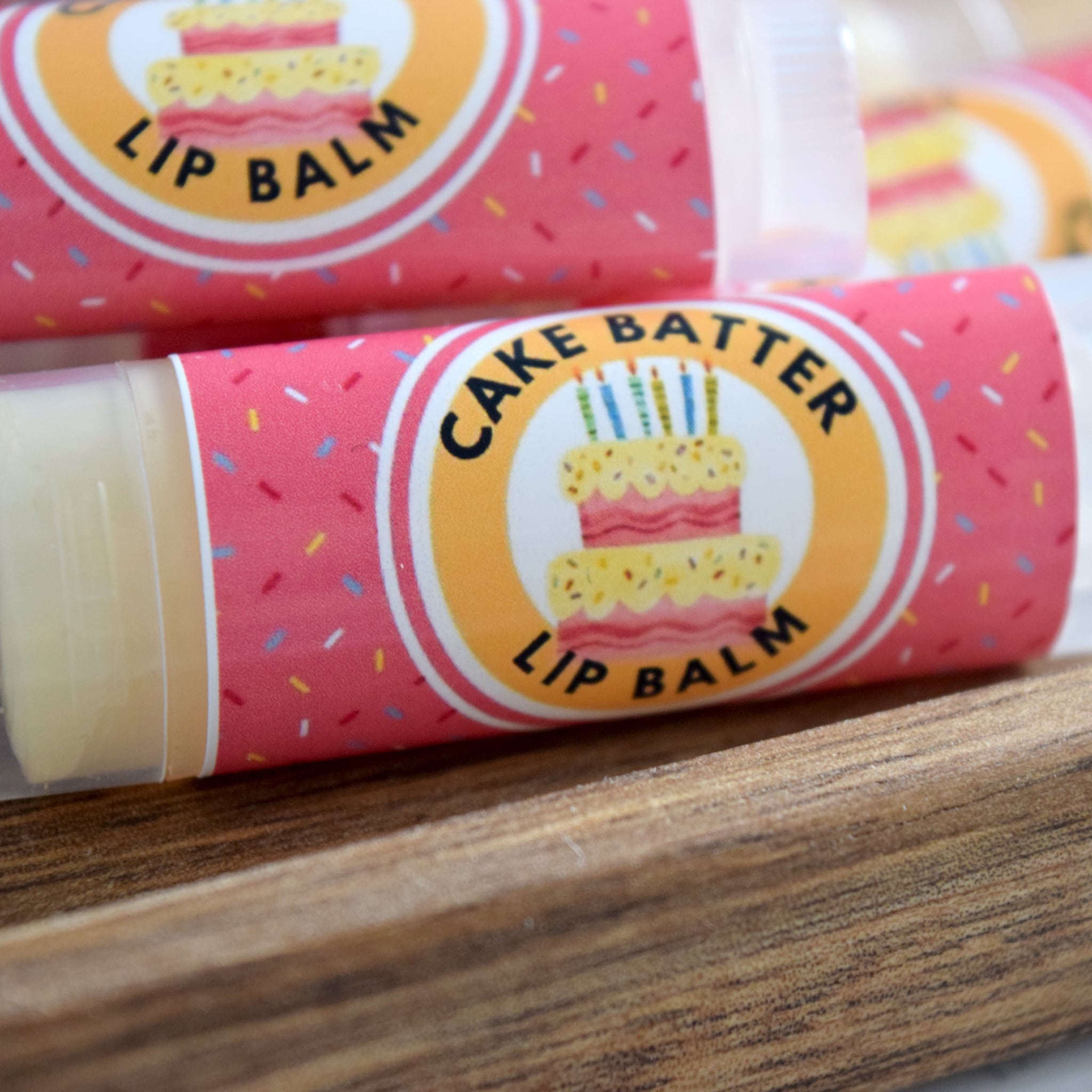 Lip balm tubes with pink sprinkle pattern, clear plastic, and Cake Batter label