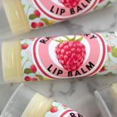 Lip balm tubes with floral pattern, pink and white label, and raspberry graphic