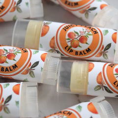 Lip balm tubes with peach fruit pattern and "Juicy Peach" text, clear plastic cap