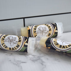 Lip balm tubes with floral pattern, white text, and clear caps on a marble surface