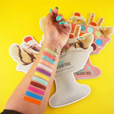 Eyeshadow palette with colorful swatches on arm, Sugary Cosmetics brand, banana split design