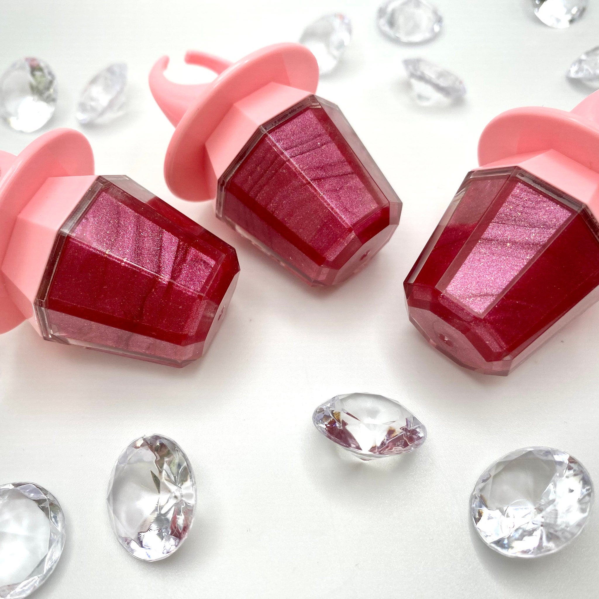 Lip gloss raspberry color with pink ring-shaped applicator and clear container