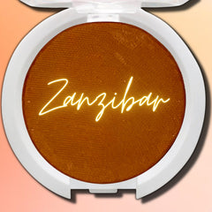 Hand applying vegan Zanzibar pressed eyeshadow with a brush, showcasing rich pigment and smooth blendability.