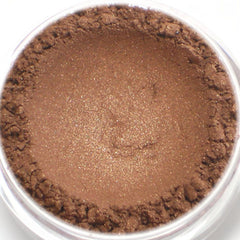 Close-up of bronze brown mineral eyeshadow being applied to eyelid with fingertip
