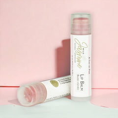 Lip balm with pink tint, clear plastic tube, and Wild Jasmine Skincare branding