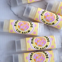 Lip balm tubes with yellow and pink labels, clear plastic caps, and text "Pink Lemonade