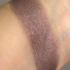 Woman applying shimmering taupe eyeshadow with a blending brush for a soft smoky eye effect