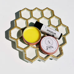 Lip balm with yellow, white, and gold honeycomb tray, Angelip brand visible