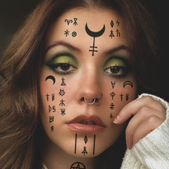 Sheet of delicate Wiccan-inspired face tattoos with intricate moon and herb designs on translucent backing