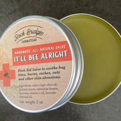 Lip balm jar with green salve, silver metal rim, and "It'll Bee Alright" label